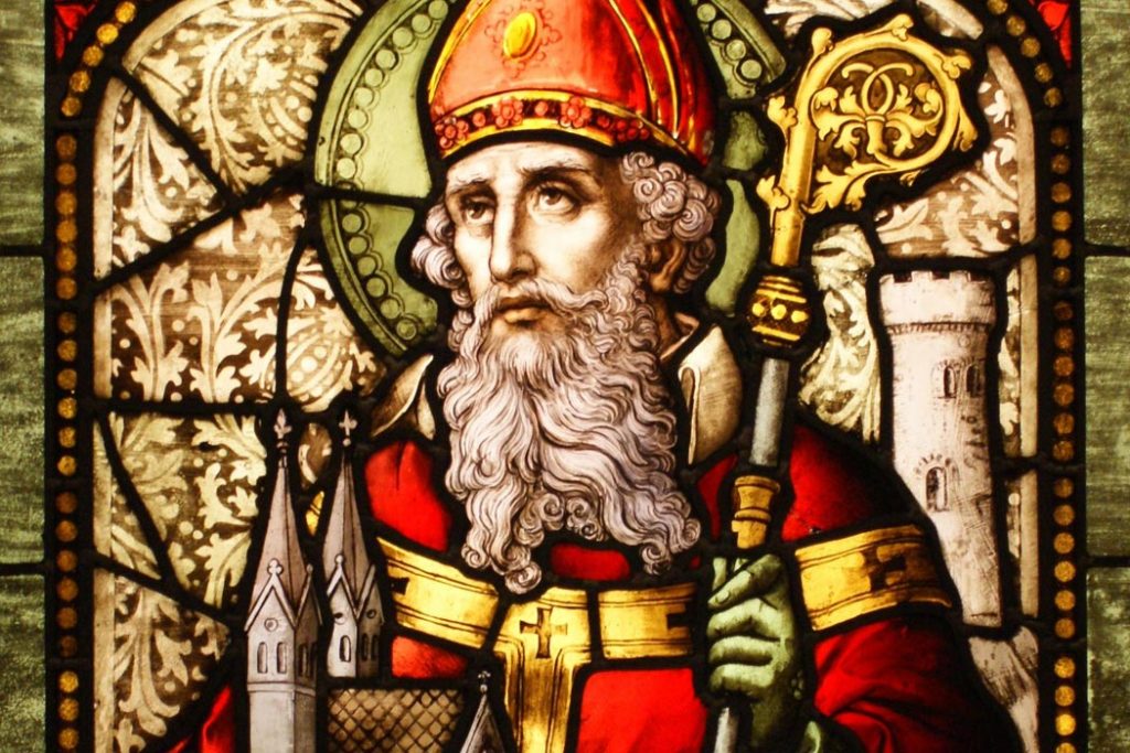 Stained Glass window depicting St Patrick with a  crock and a castle